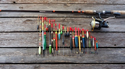 Fishing floats in different shapes and fishing rod on wooden background © mtmmarek