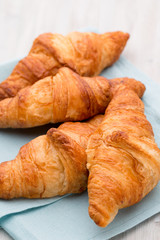 Tasty buttery croissants on old wooden table.