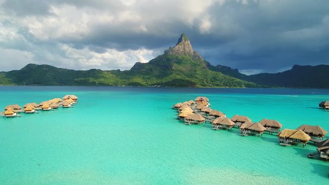 Aerial view of tropical paradise of Bora Bora, turquoise crystal clear water of scenic lagoon, typical overwater bungalows - South Pacific Ocean, French Polynesia, 4k UHD
