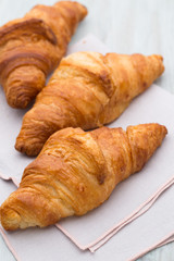 Tasty buttery croissants on old wooden table.