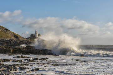 Fototapeta na wymiar Landscape image of Mumbles lighthouse with waves crashing against the rocks 