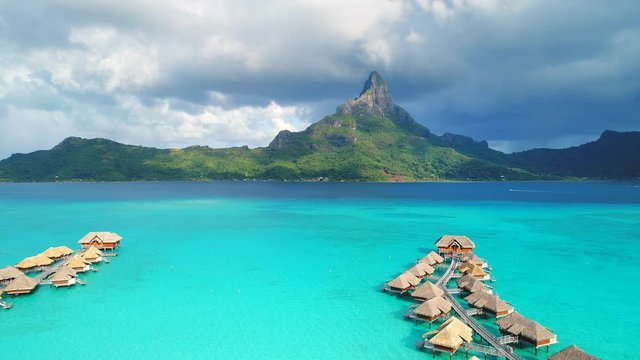 Aerial view of tropical paradise of Bora Bora, turquoise crystal clear water of scenic lagoon, typical overwater bungalows - South Pacific Ocean, French Polynesia, 4k UHD
