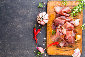 Prosciutto with rosemary on a black background.