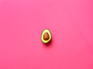 Avocado with seed isolated in fuscia background viewed from above - flatlay look