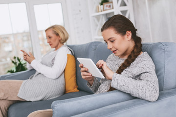 Modern communication. Cheerful brunette female sitting in semi position while looking at screen of her devise
