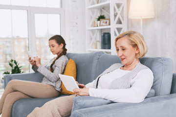 Just relax. Delighted blonde expressing positivity while using her gadget with pleasure