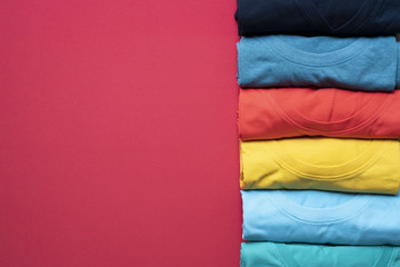 close up of rolled colorful clothes on red background