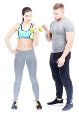 Gym trainer assisting fit young woman doing dumbbell exercise