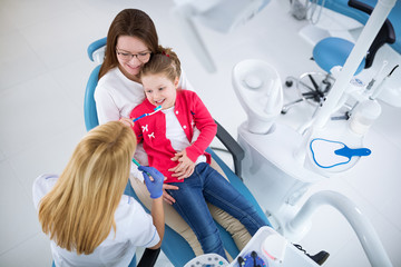 Dentist with sterile mask and dental instruments held exam teeth of patient