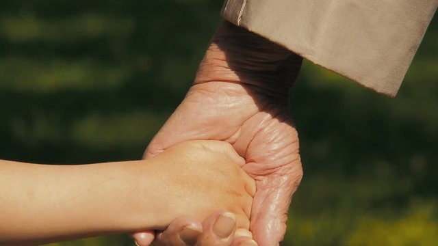 Elderly with a child by the hand. Holds the child by the hand