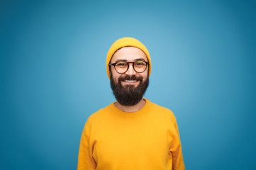 Smiling happy bearded hipster on blue