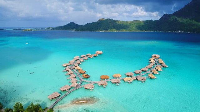 Aerial view of tropical paradise of Bora Bora, turquoise crystal clear water of scenic lagoon, typical overwater bungalows - South Pacific Ocean, French Polynesia, 4k UHD