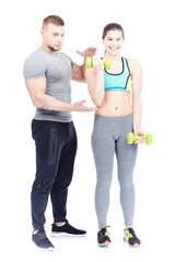 Male fitness instructor assisting fit young woman doing dumbbell exercise