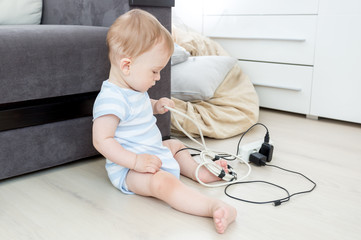 9 months old baby boy playing and pulling electric cables and wires. Children in danger