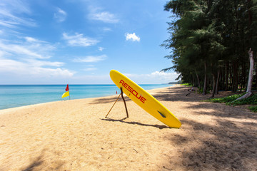 Orange rescue board and boundary flag on the beach at Mai Khao Beach, Phuket Province, Thailand