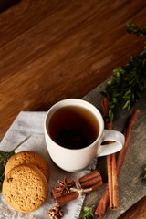Traditional Christmas tea concept with a cup of hot tea, cookies and decorations on a wooden table, selective focus
