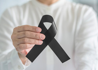 Black Ribbon symbolic bow color raising awareness on Melanoma and skin cancer prevention, sleep  disorder, mourning for the death loss of victims and terror attack concept