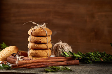 Christmas composition with pile of cookies, cinnamon and dried oranges on light wooden background, close-up.