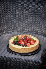 In a green garden in the nature fruit pie with strawberries and other berries. On a woven table