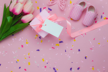 Table top view aerial image of decoration Happy Mothers day holiday background concept.Flat lay gift box & tulip flower with  kids shoe on beautiful pink paper.Pastel tone creative design mock up.