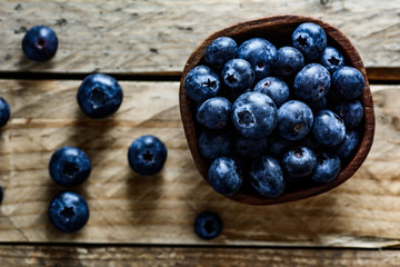 Fresh blueberries in bowl. Wooden background