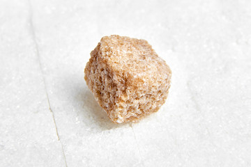 Piece brown cane unrefined sugar laying on white sugar cubes