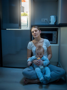 Young Mother Sleeping On Kitchen Floor While Feeding Her Baby Boy At Night