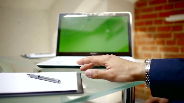 close up shot oof a man's hands who knocks his fingers on the table, next is a laptop and a folder with documents