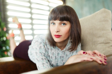 Photo of young brunette sitting on chair near window with blinds