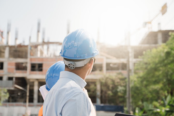 Architects And Engineer at a construction site looking at blueprints and pointing.