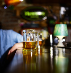 Glass of light beer on wooden bar counter.