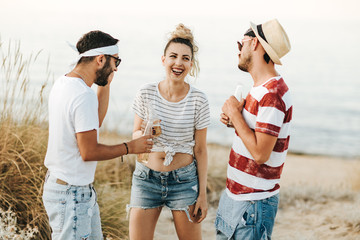 Group of happy young people at the beach talking and drinking beer.
