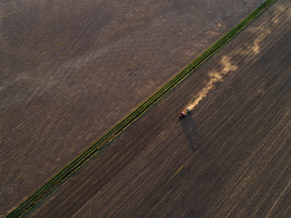 Aerial view of the tractor in the field, spring sowing work. Sowing of wheat in a field at sunset