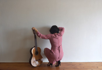 woman from behind with guitar on a wall