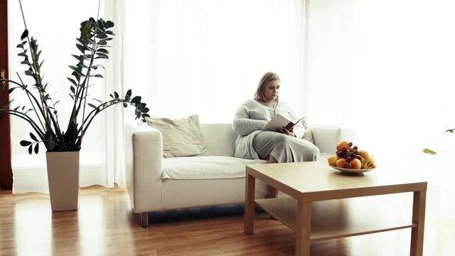 An attractive overweight woman at home, reading a book.