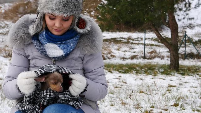 Young worried woman taking care of her little dog pinscher ratter prazsky krysarik feeling cold during winter.