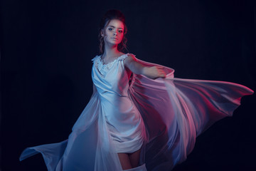 Fashion portrait of young elegant girl in white dress. Black background, studio shot.