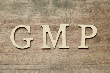 Fototapeta premium English alphabet in word GMP (Abbreviation of good manufacturing practice) on wood background