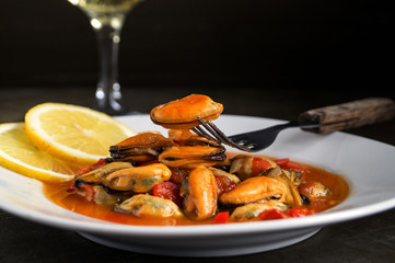 mussels in tomato sauce on dark background.