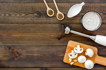 Cook cream soup with mushrooms. Champignon, cream, spices and blender on dark wooden background top view copy space