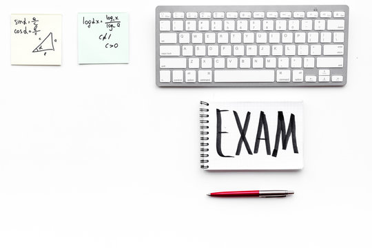 Exam concept. Lettering Exam in notebook on student's work desk on white backgrond top view copy space