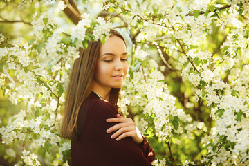 young woman with clean skin near a blooming apple tree. portrait of girl in spring park.