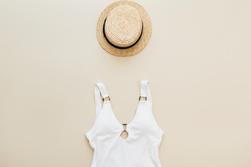 Flat lay summer fashion composition. Women's swimsuit, straw on pastel beige background. Flat lay,...