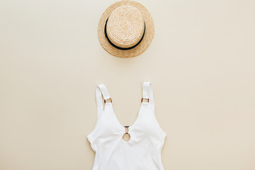 Flat lay summer fashion composition. Women's swimsuit, straw on pastel beige background. Flat lay, top view minimal beach concept.