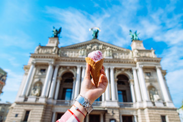 Obraz premium first-person view. woman hold ice cream in hand old european building on background