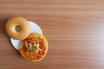 Snacks with Donut bread and Pizza in a white plate on wooden table Topview. 