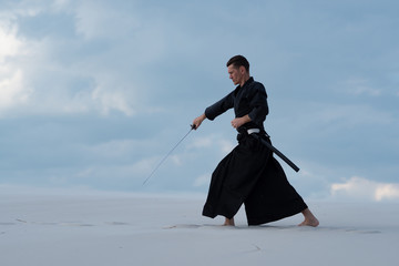 Focused man is practicing martial arts in the desert