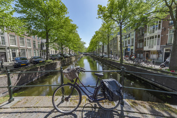 Fototapeta premium Iconic scene of Amsterdam with the bicycle parked on a bridge over a calm water canal, Netherlands