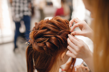 Fototapeta premium Woman hairdresser making hairstyle to blonde girl in beauty salon.
