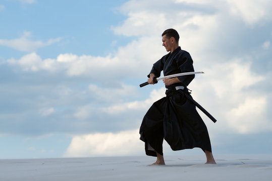 Man practicing Japanese martial art in desert